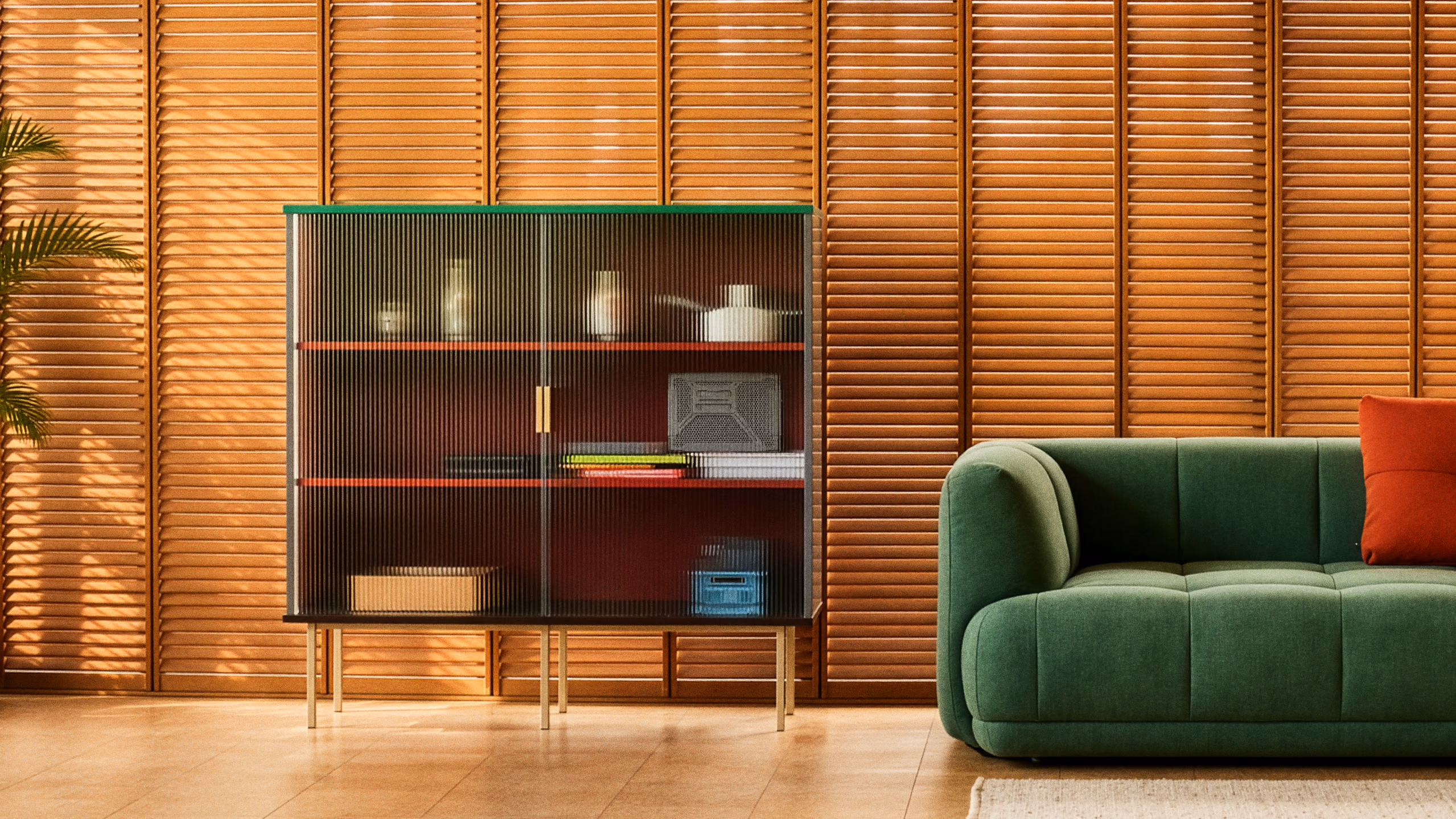 Oki Home displayed in a cabinet beside a green sofa.